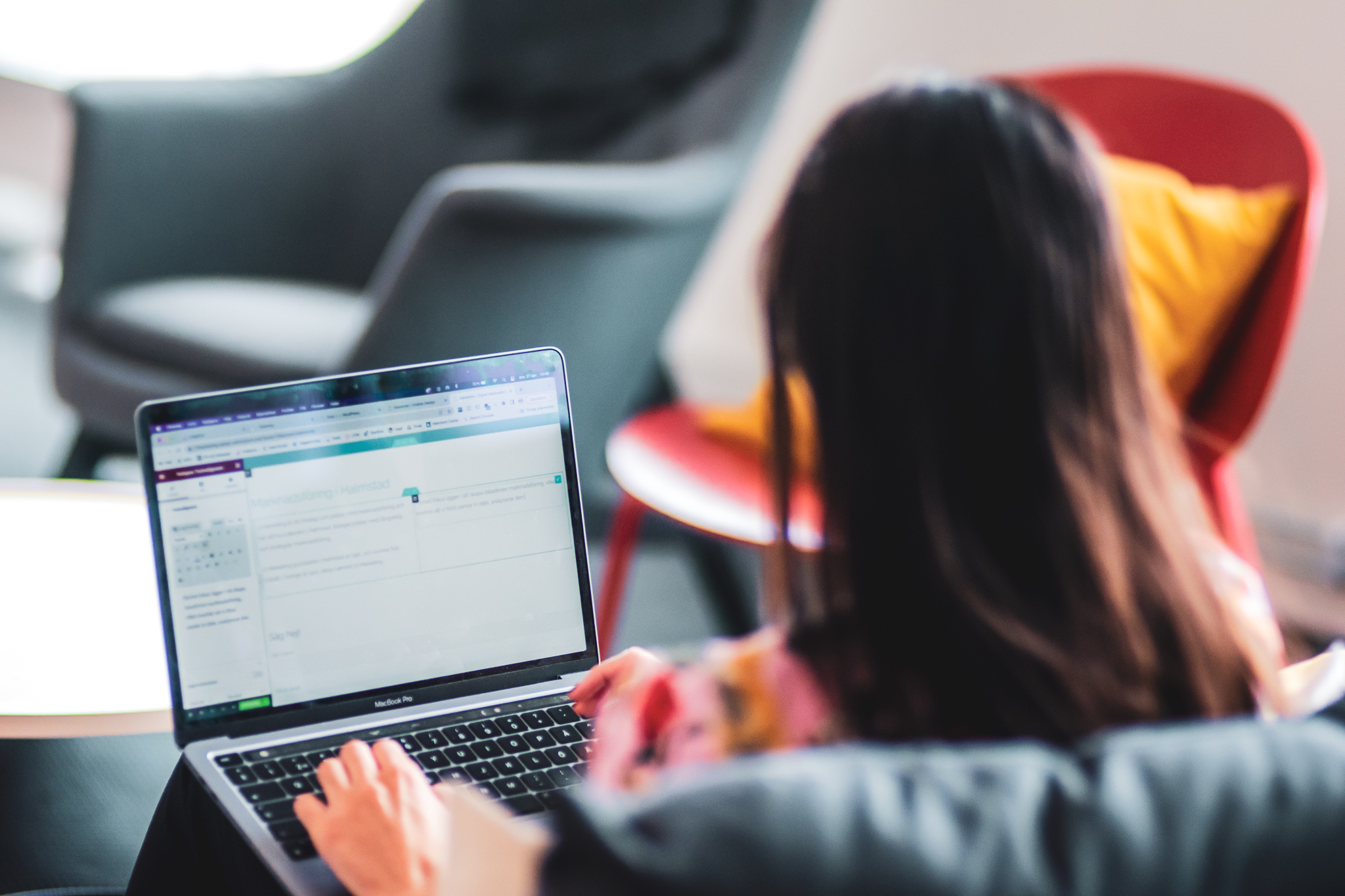 En person sedd bakifrån som sitter i en soffa och tittar på en laptop
